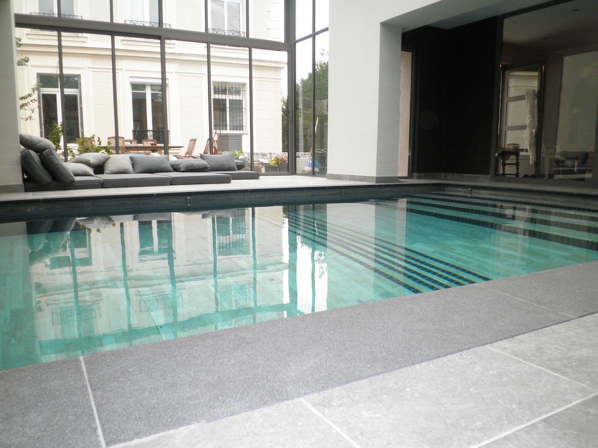 Grande piscine intérieure avec margelles en pierre 